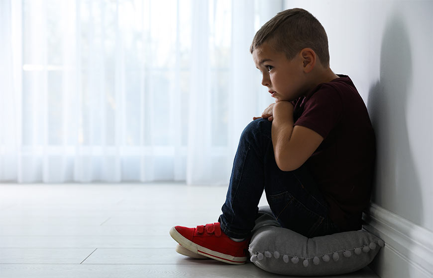 Photo of a little boy huddled in the fetal position