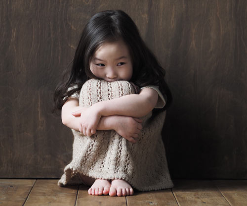 Photo of a little girl huddled in the fetal position