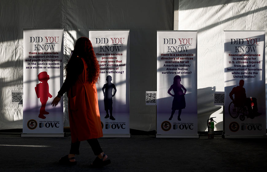 Photo of a woman walking past victim support campaign signage