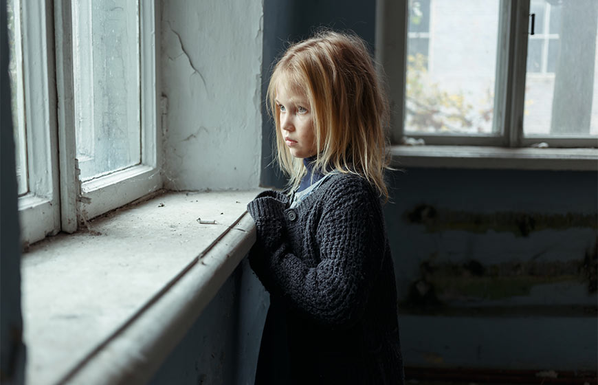 Photo of a little girl with dirt on her face looking out a window
