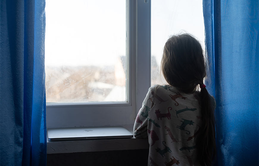 Photo of a little girl looking out a window