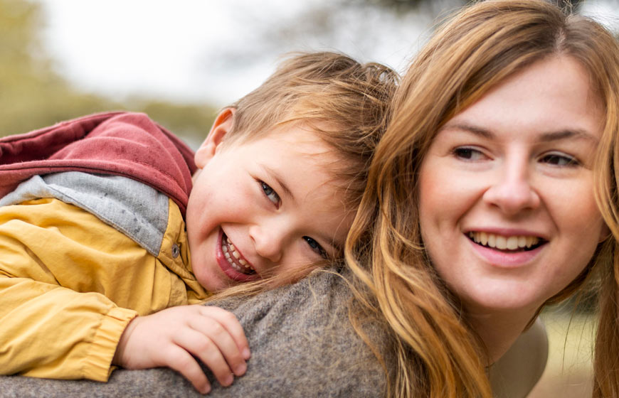 Photo of a mother holding her young son on her back